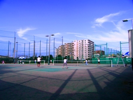 青し空と、マンションを背にしたテニスコートが映っている写真