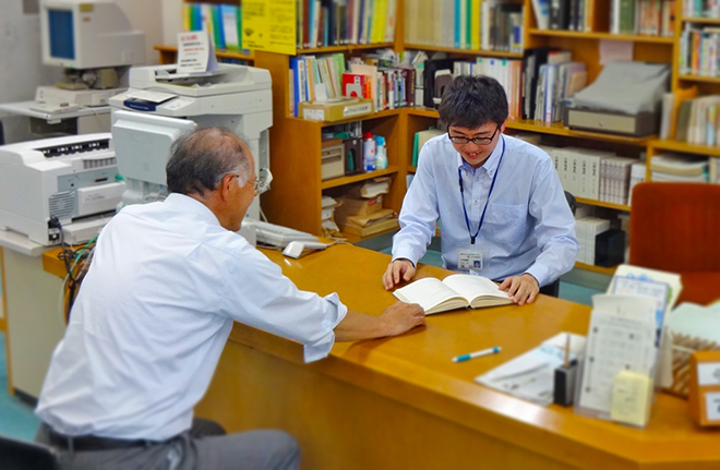 図書館の男性職員が、カウンター越しに利用者の話を聞いている写真